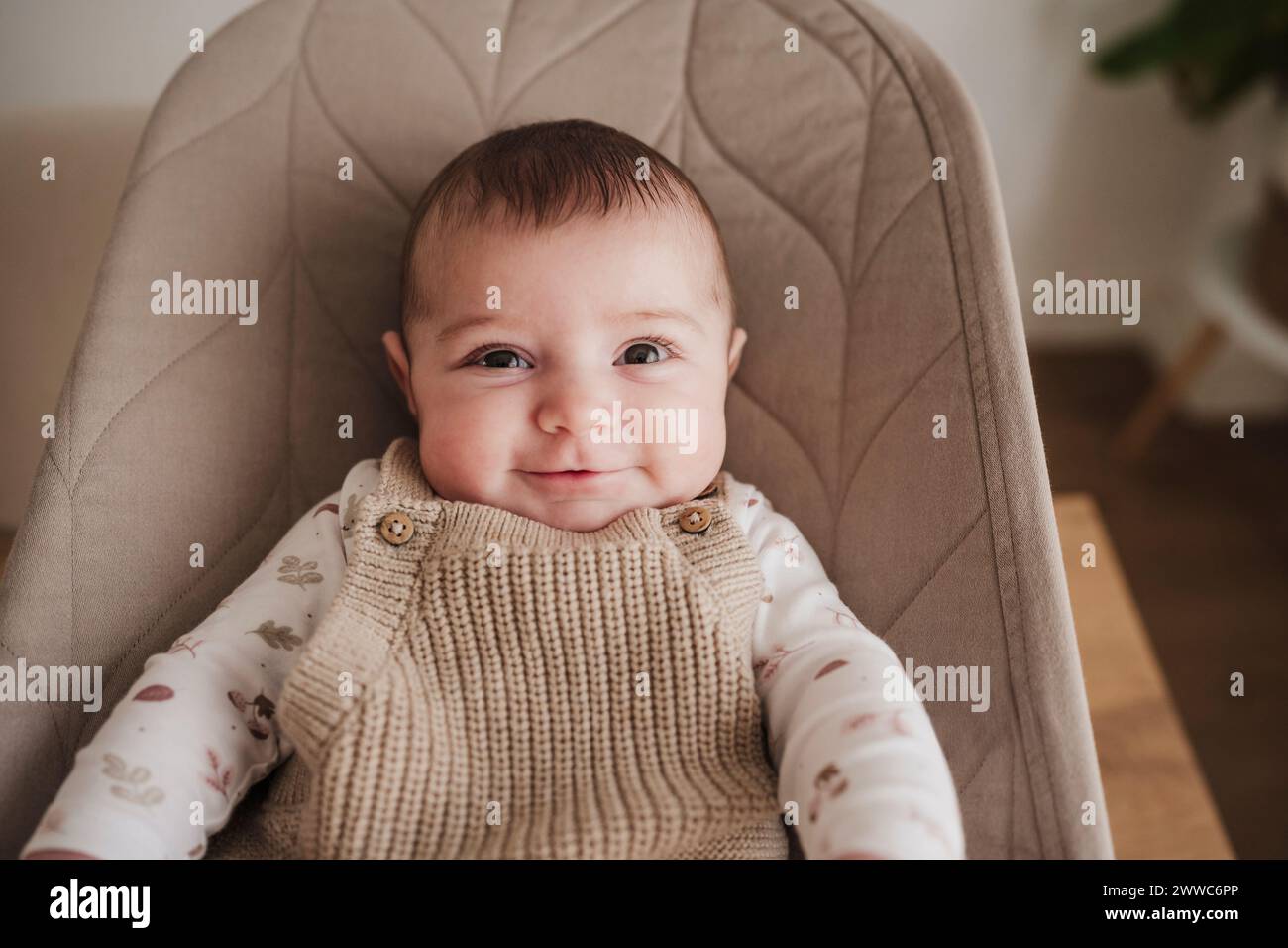 Happy baby girl sitting on bouncer chair Stock Photo