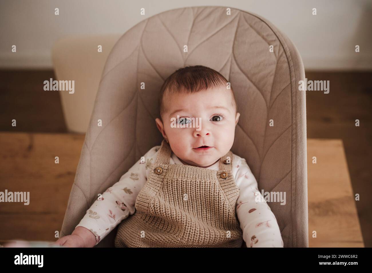 Smiling baby girl sitting on bouncer chair Stock Photo