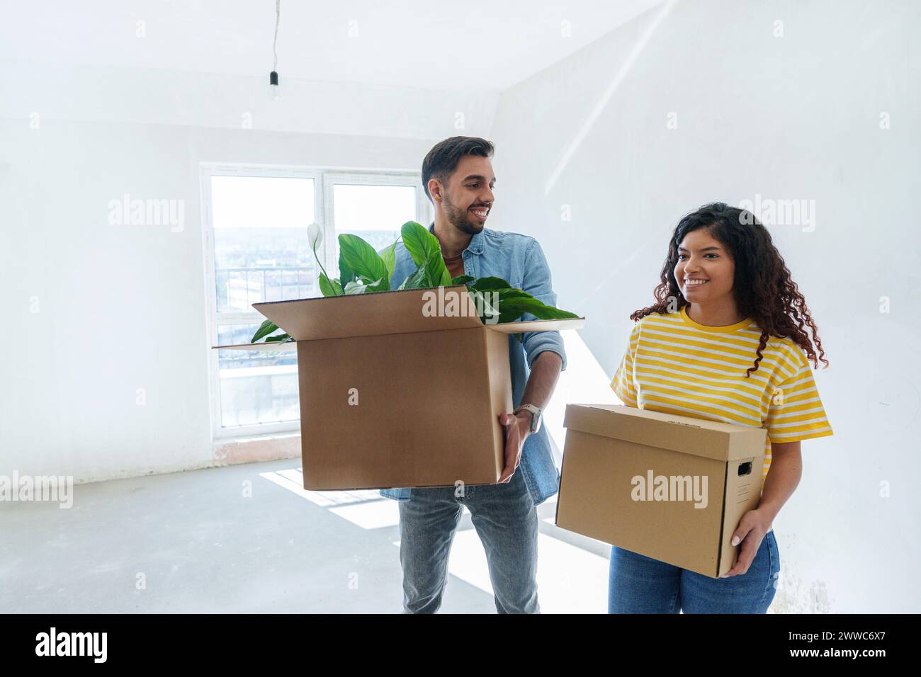 Smiling couple carrying cardboard boxes at new home Stock Photo