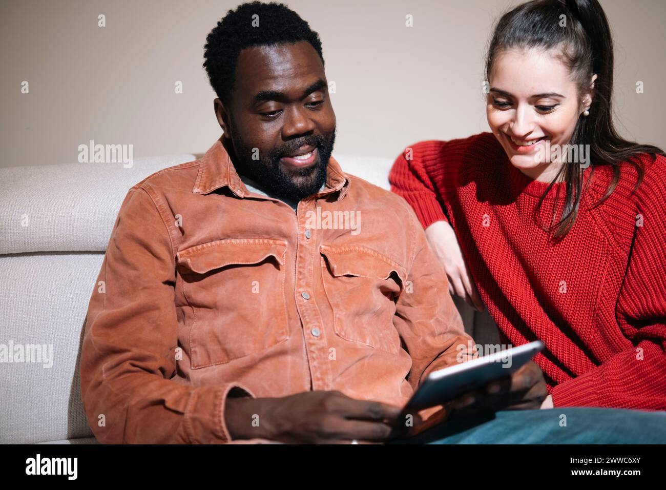 Smiling couple talking and using tablet PC at home Stock Photo
