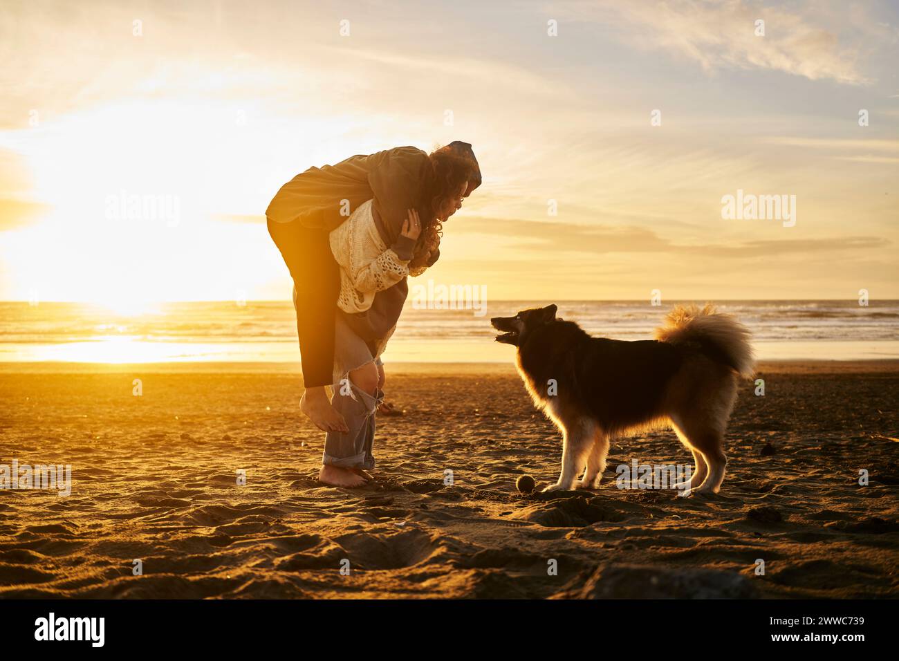 Happy young couple enjoying with dog at beach Stock Photo - Alamy