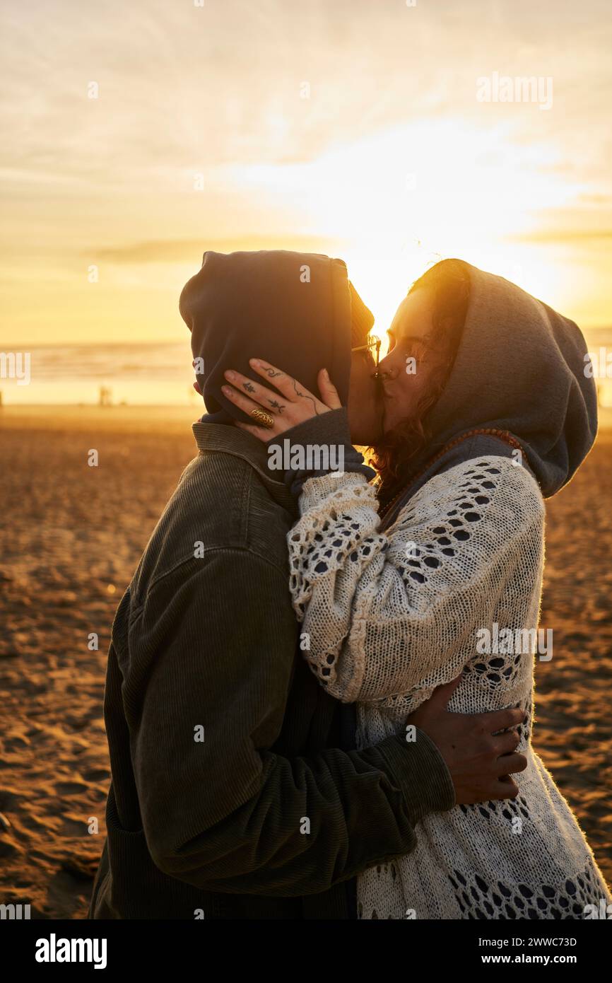 Young couple kissing on beach at sunset Stock Photo