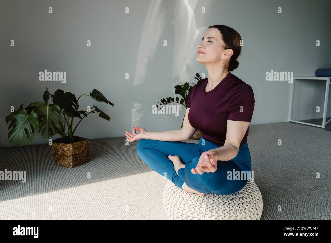 Smiling woman meditating on seat at home Stock Photo