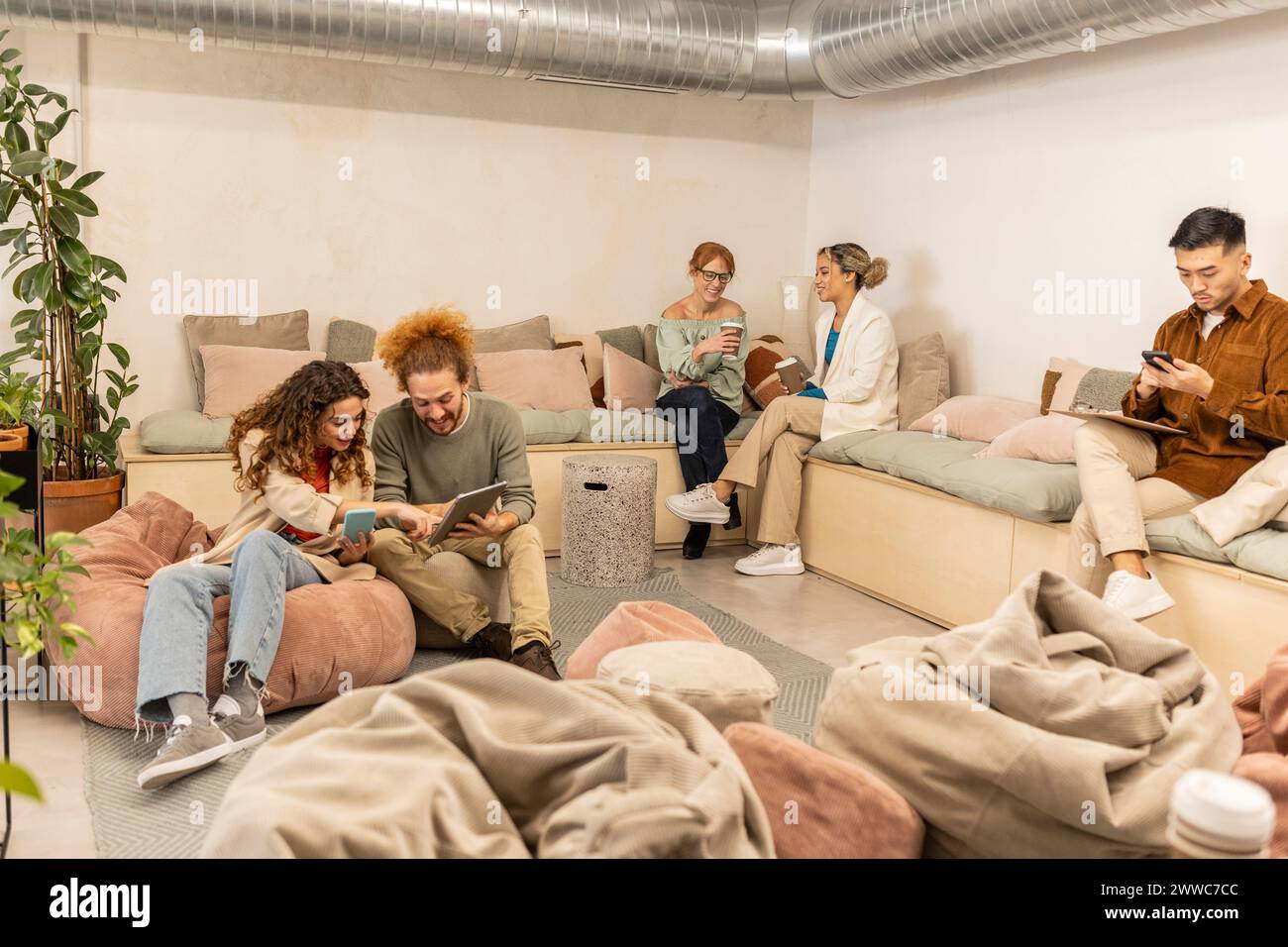 Diverse business colleagues using wireless technologies and talking on break at office Stock Photo