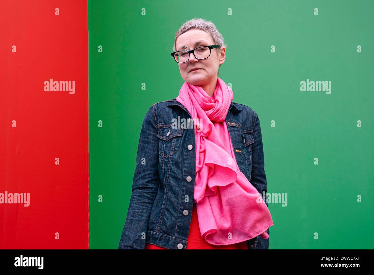 Mature woman wearing eyeglasses standing in front of green wall Stock Photo