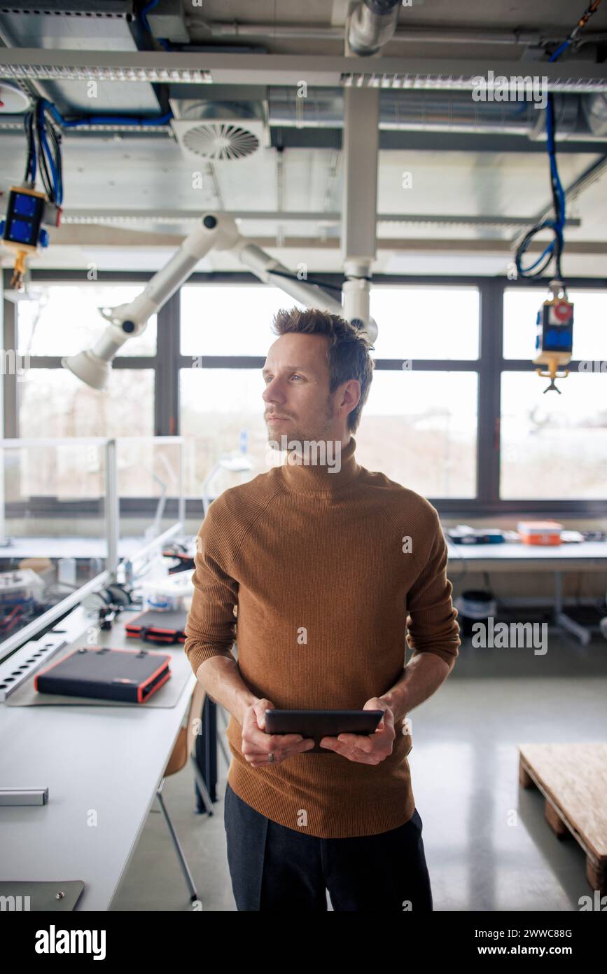 Thoughtful engineer holding tablet PC Stock Photo