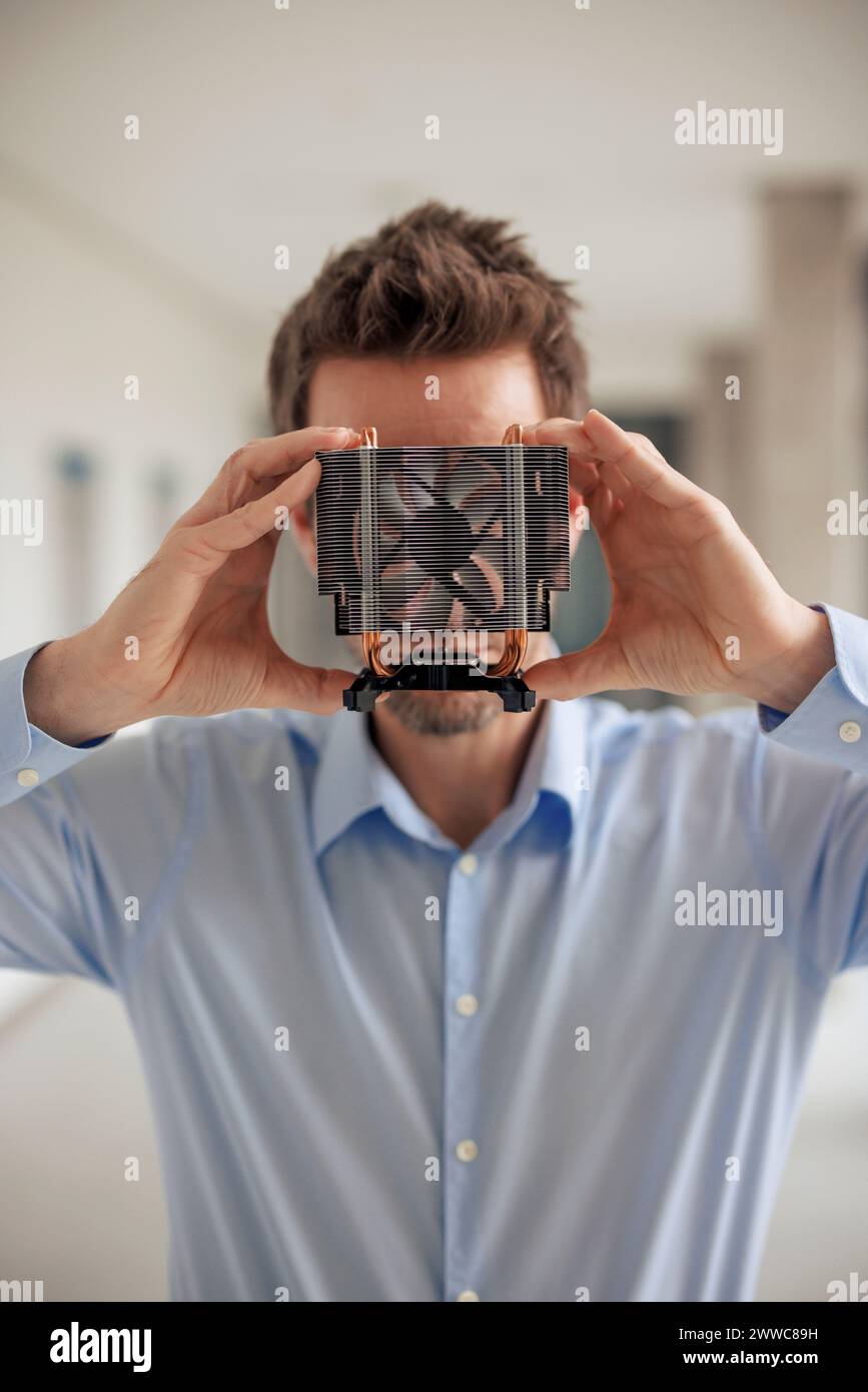 Engineer covering face with CPU fan at workshop Stock Photo