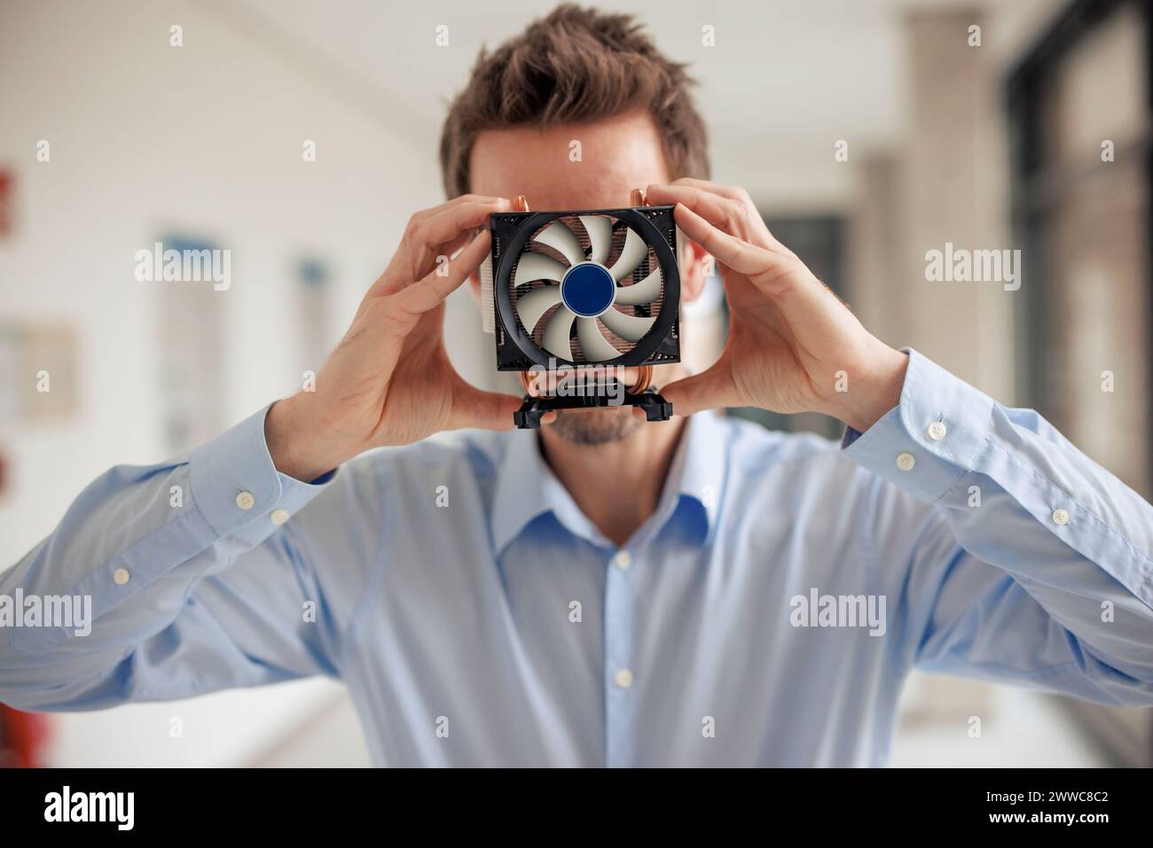 Mature engineer covering face with CPU fan at workshop Stock Photo