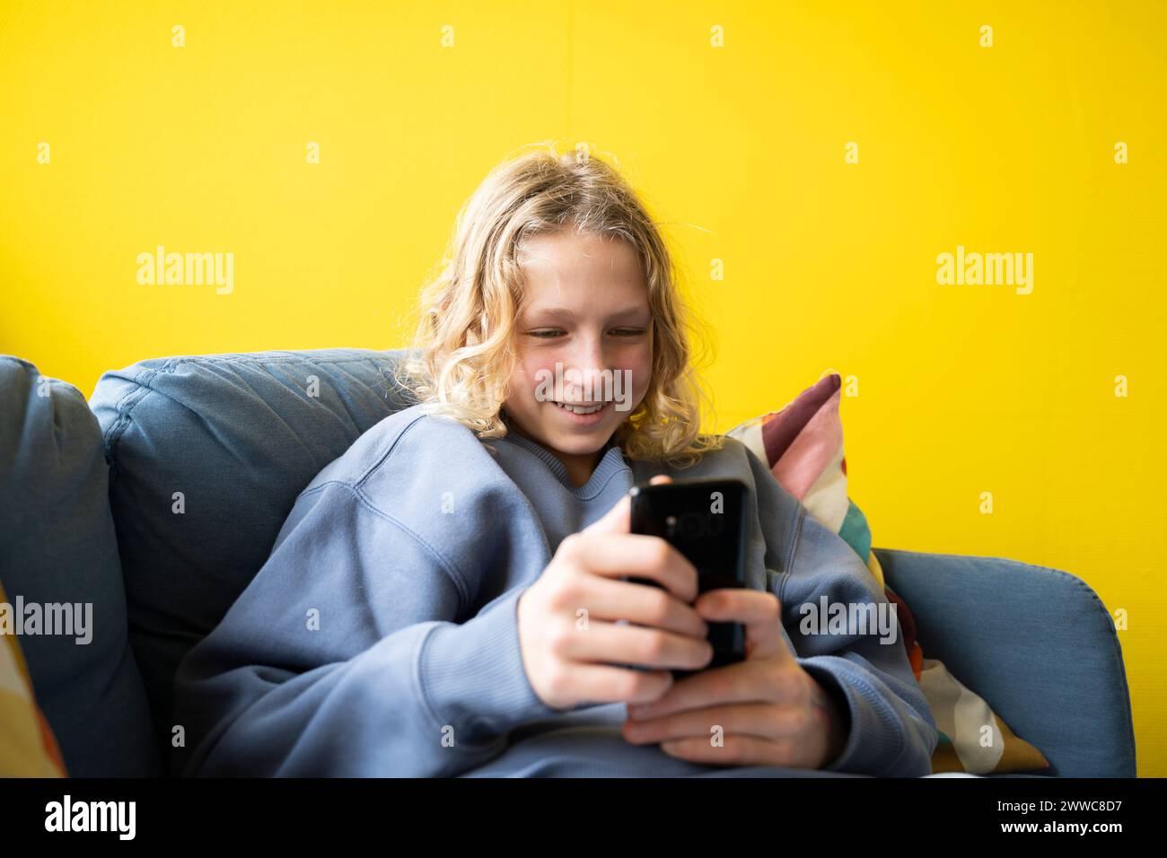 Smiling boy using smart phone at home Stock Photo