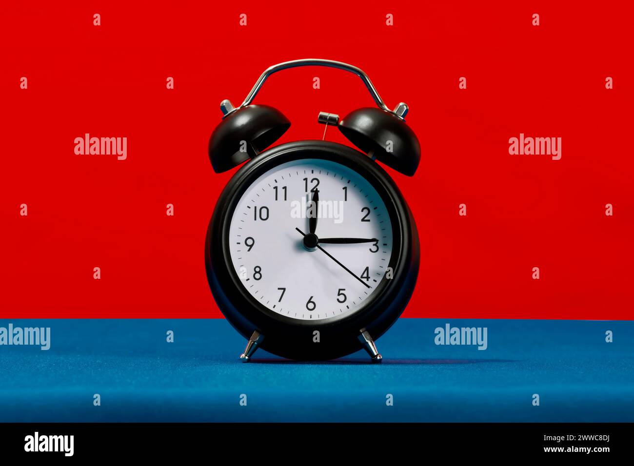Retro black alarm clock against red background Stock Photo
