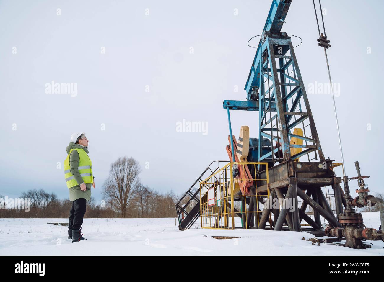 Engineer examining drilling tower at oil production field in winter Stock Photo