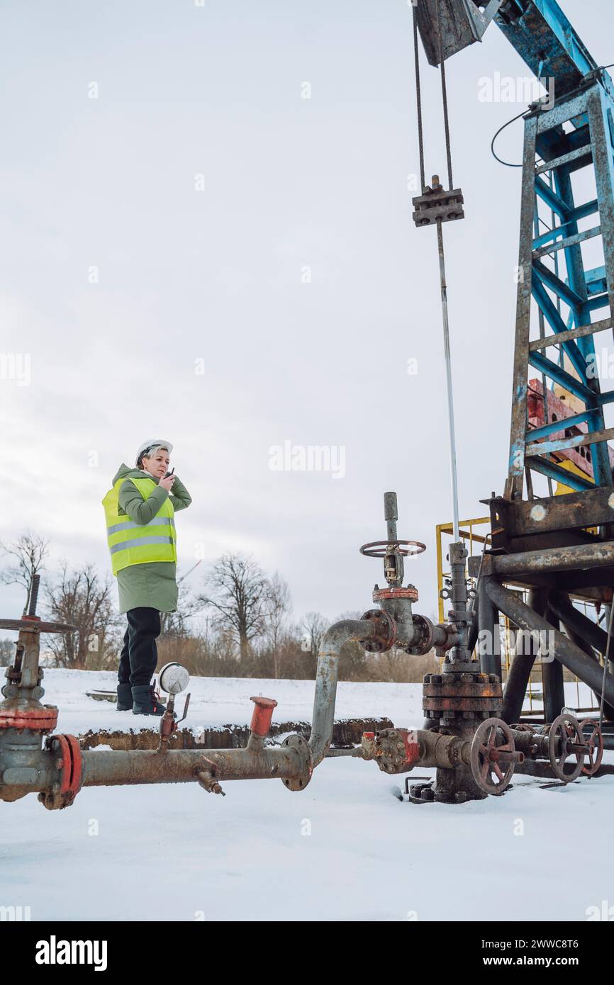 Engineer standing near drilling tower at oil production field in winter Stock Photo