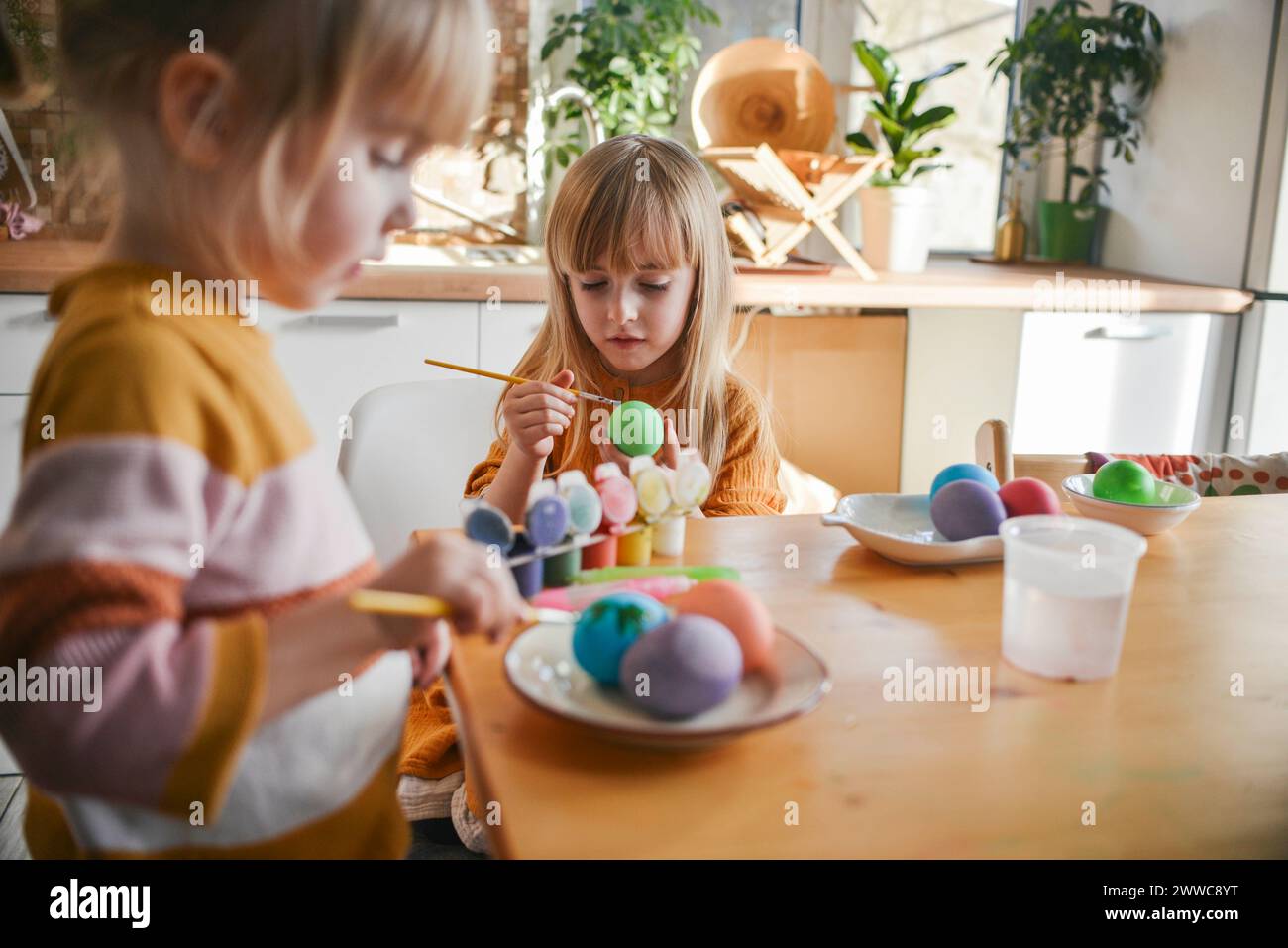 Sisters painting Easter eggs at home Stock Photo
