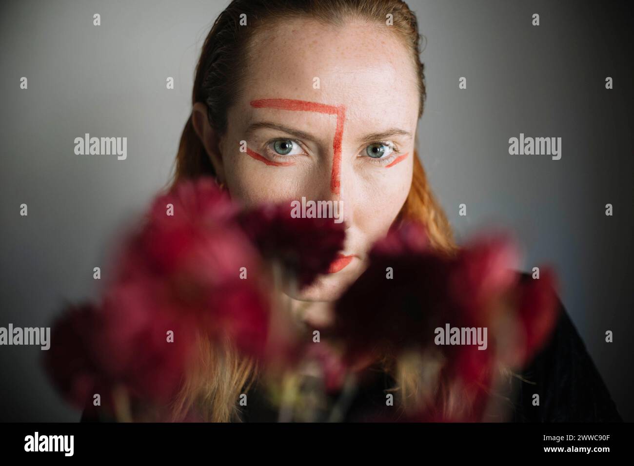 Serious woman with lipstick stain on face against gray background Stock Photo