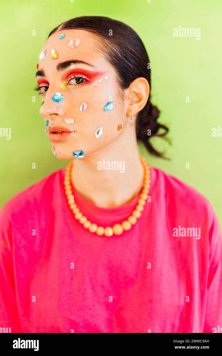 Woman with gem stickers on face against green background Stock Photo