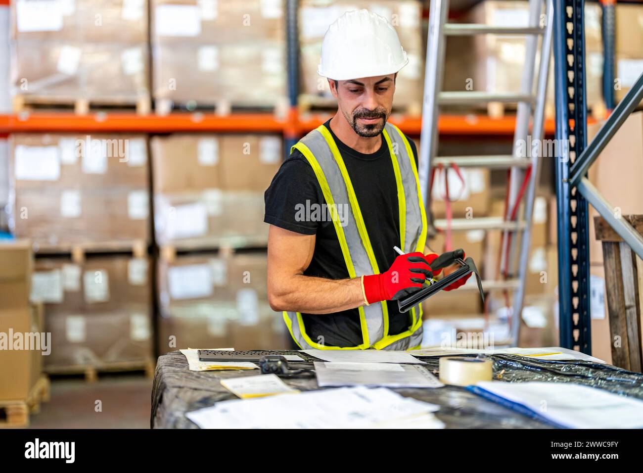Worker examining documents with tablet PC at warehouse Stock Photo