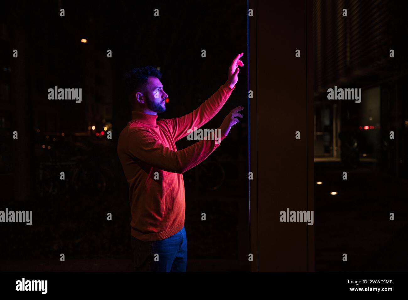 Man using touch screen kiosk machine on street at night Stock Photo