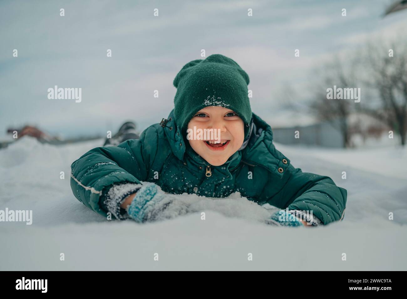 Happy boy lying down and playing on snow Stock Photo