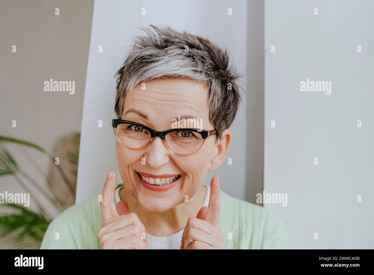 Happy mature woman wearing eyeglasses at home Stock Photo