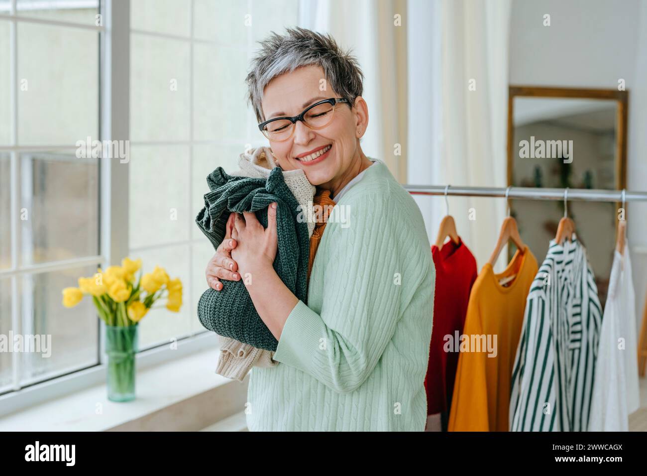 Happy woman hugging clothes at home Stock Photo - Alamy