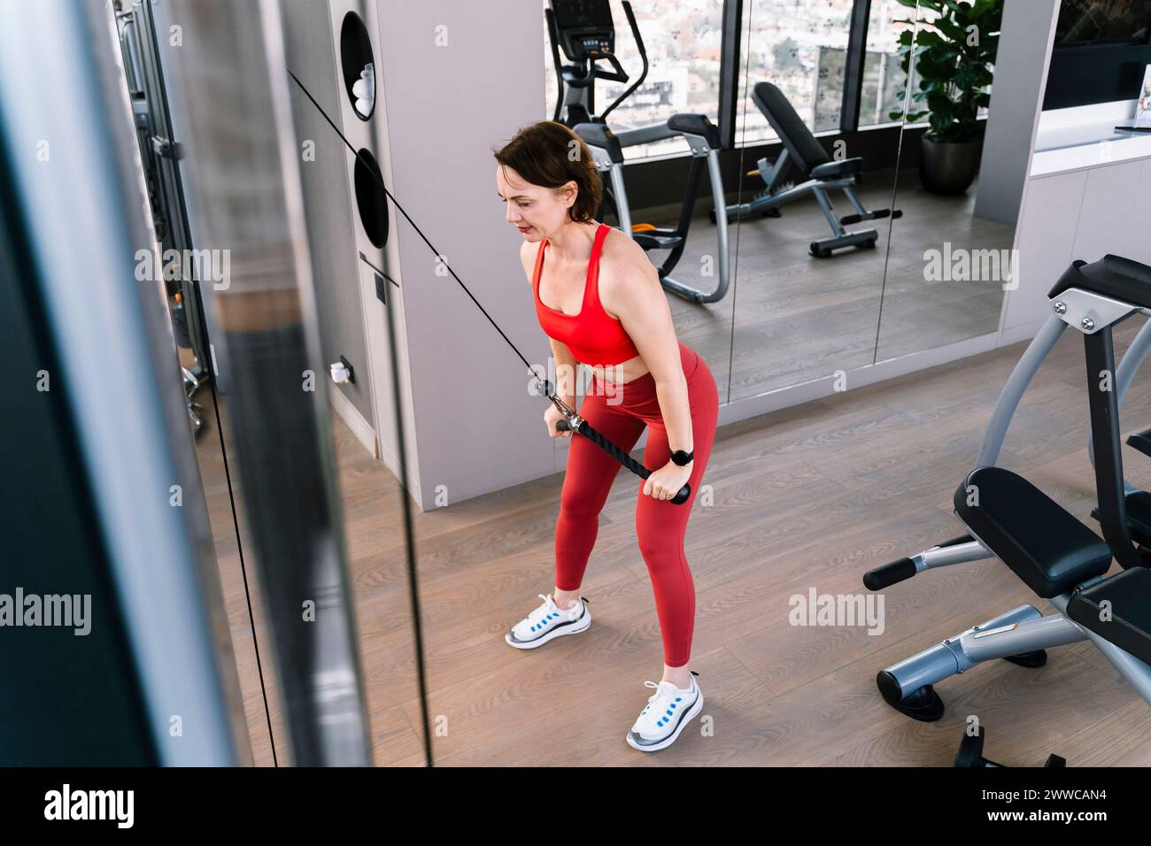 Woman exercising on cable crossover machine at gym Stock Photo