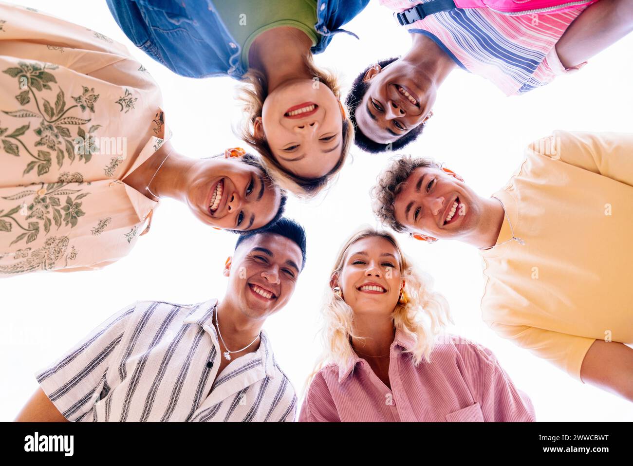 Multiethnic group of young friends with colorful clothing bonding outdoors in the city, concepts about youth and lifestyle - Barcelona, Spain Stock Photo