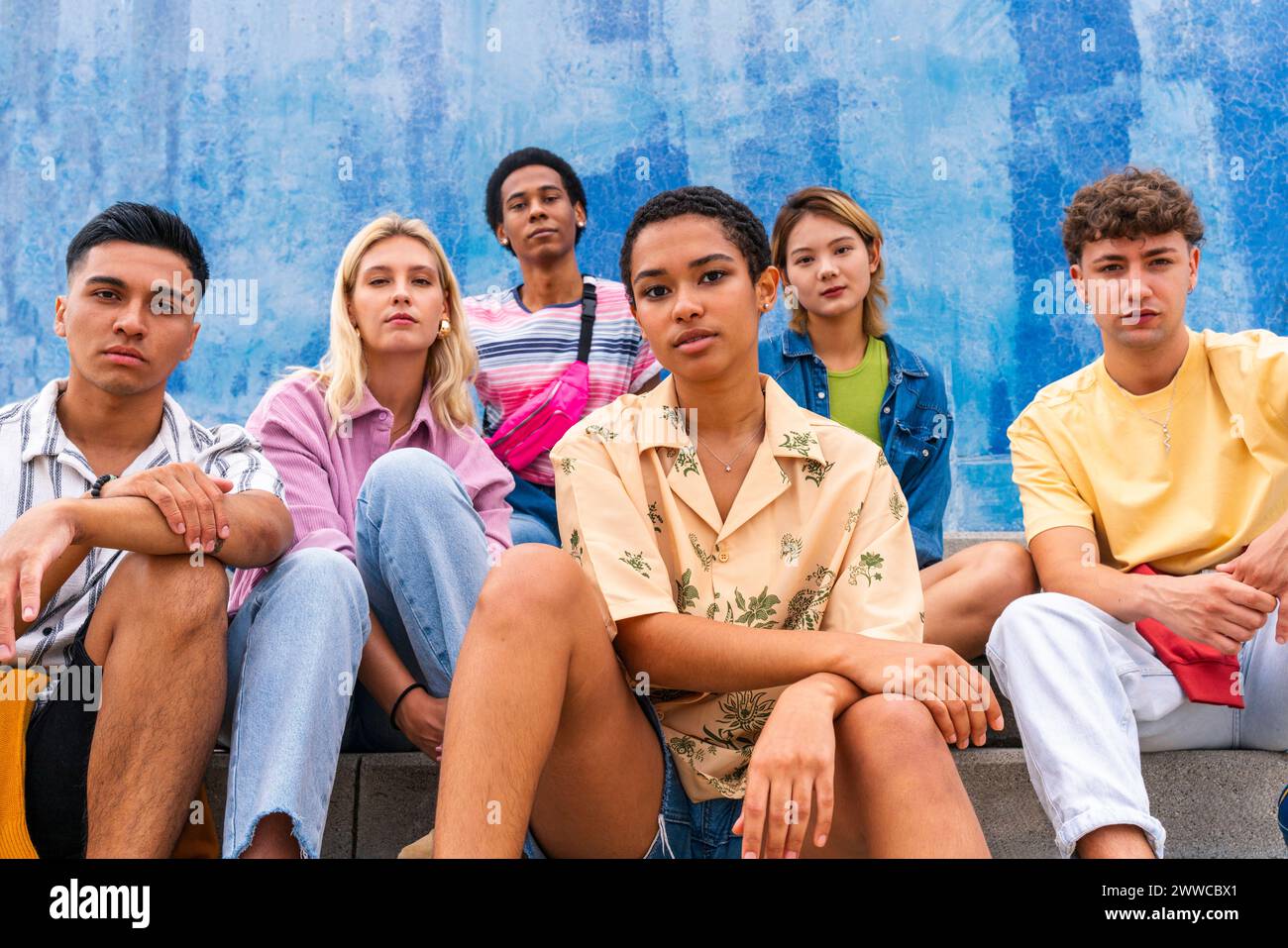 Confident young people sitting on steps in front of wall Stock Photo
