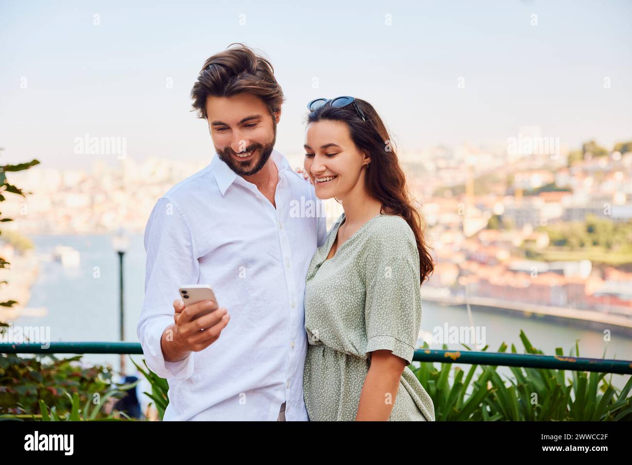 Happy young couple using smart phone on sunny day Stock Photo