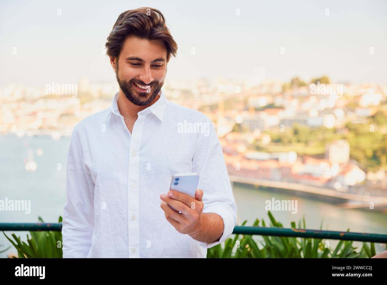 Smiling young man using smart phone Stock Photo