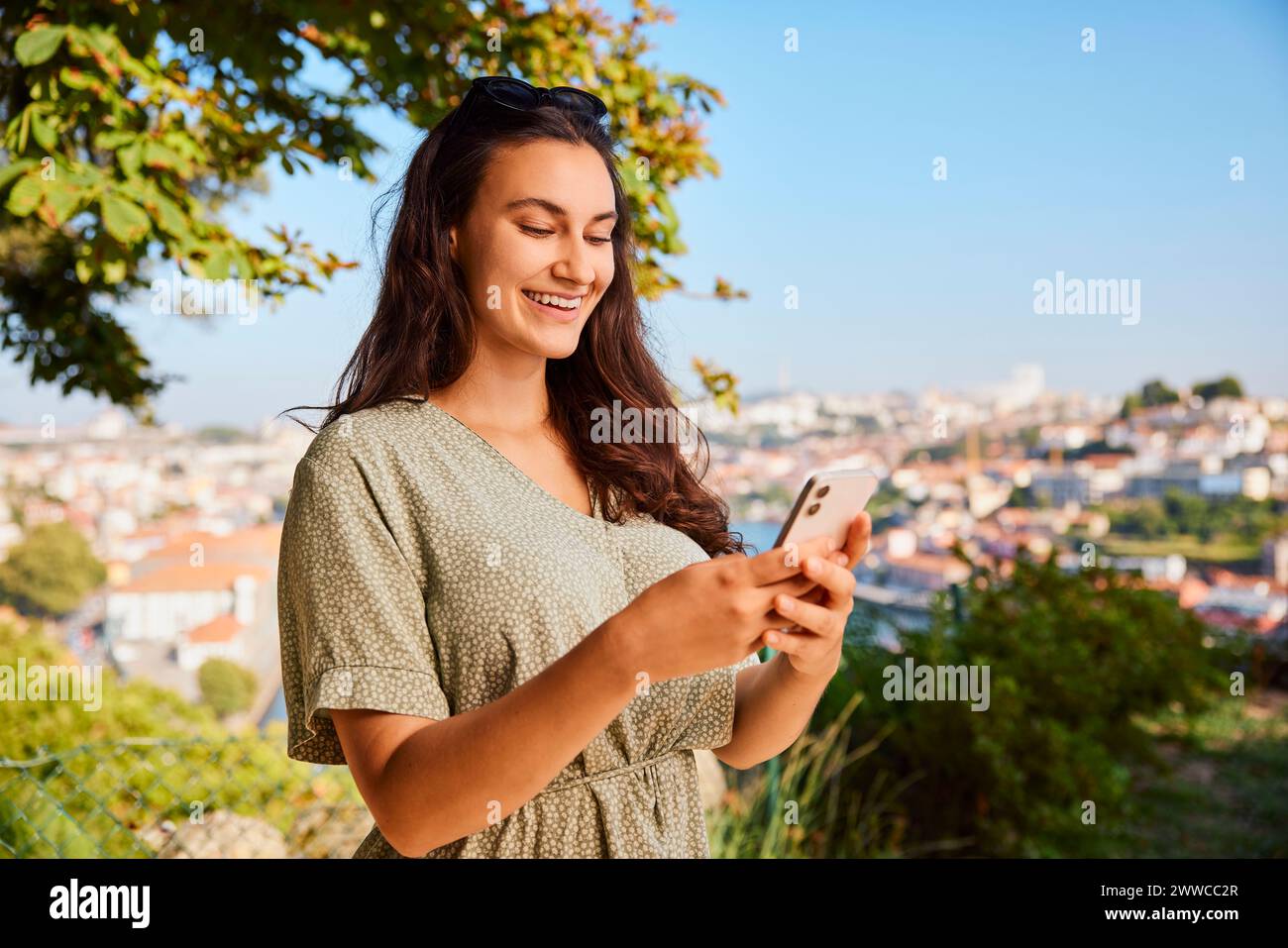 Smiling young woman using smart phone Stock Photo