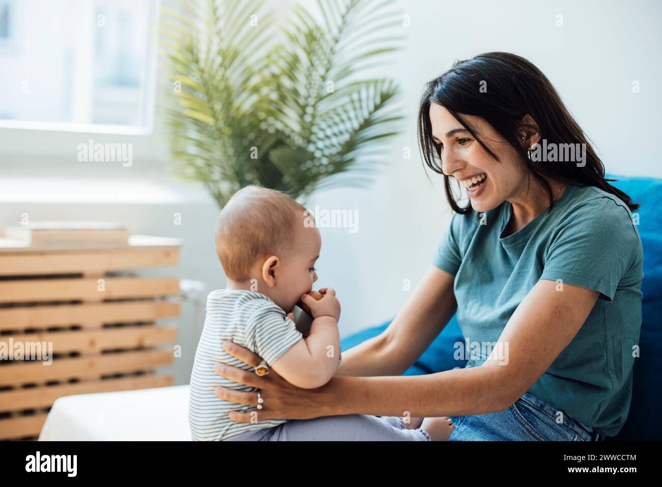 Happy mother playing with daughter sitting in bedroom Stock Photo