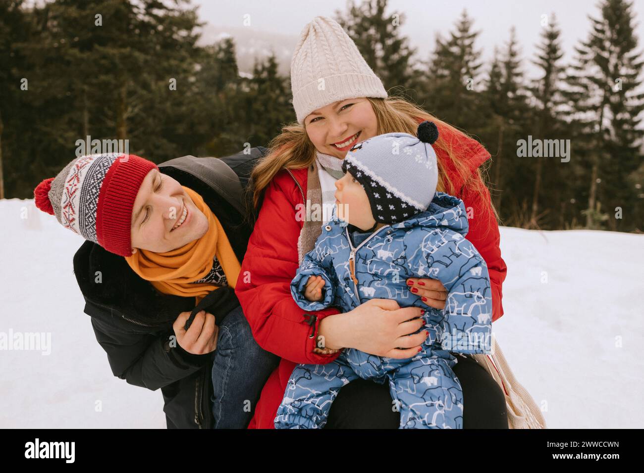 Smiling woman with baby boy near man in winter forest Stock Photo