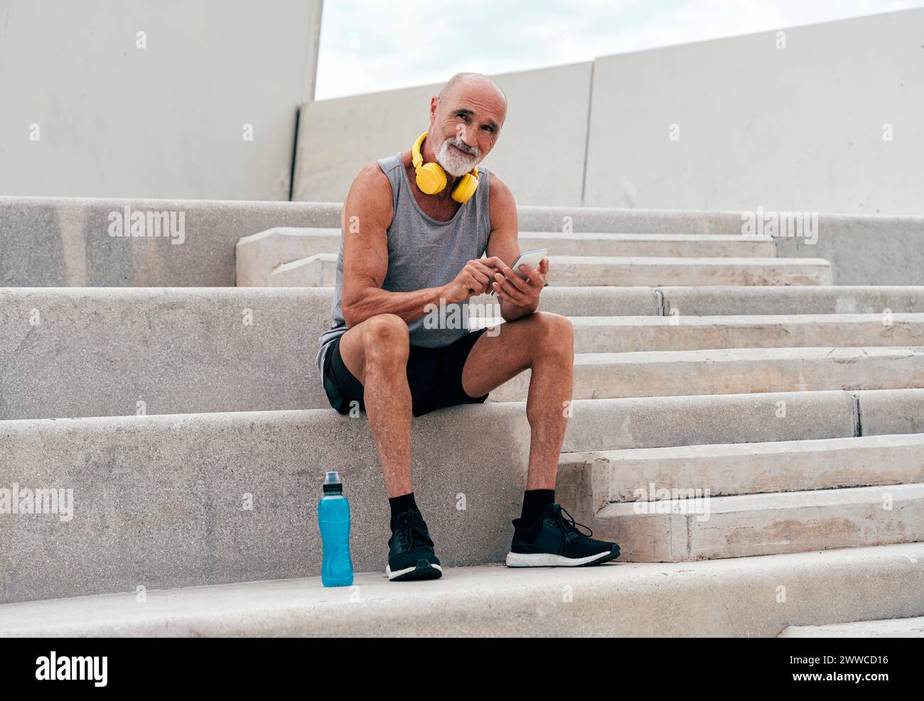 Retired senior man using smart phone sitting on staircase Stock Photo