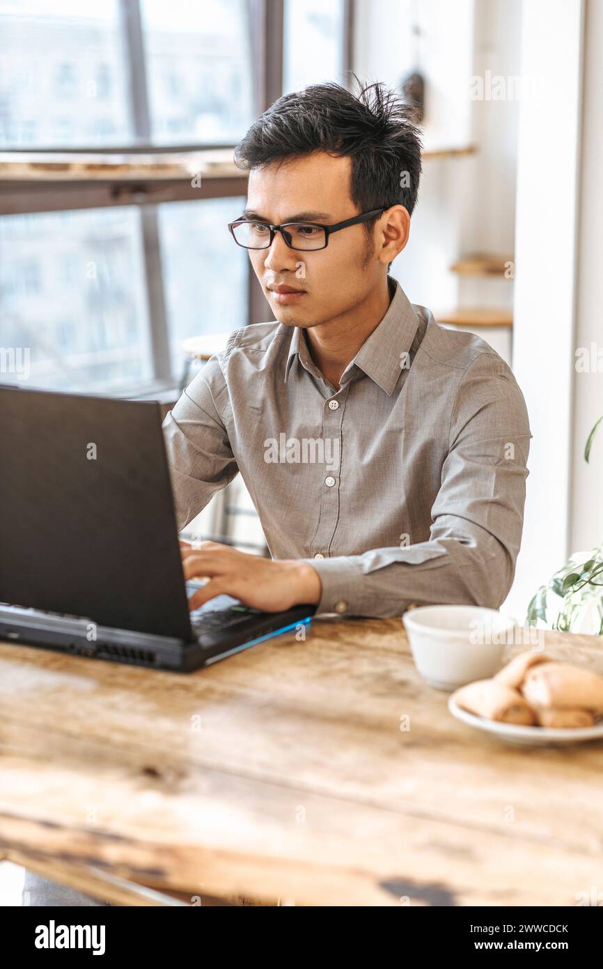 Confident young programmer using laptop for coding at creative startup Stock Photo