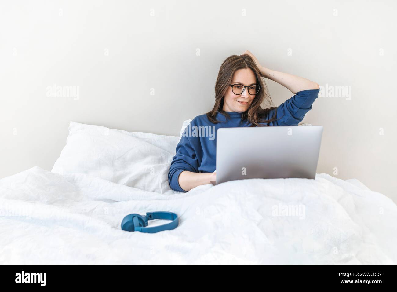 Programmer using laptop sitting on bed at home Stock Photo