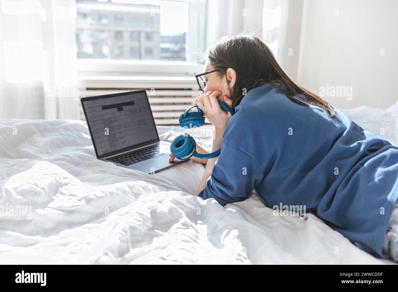 Programmer using laptop lying on bed at home Stock Photo
