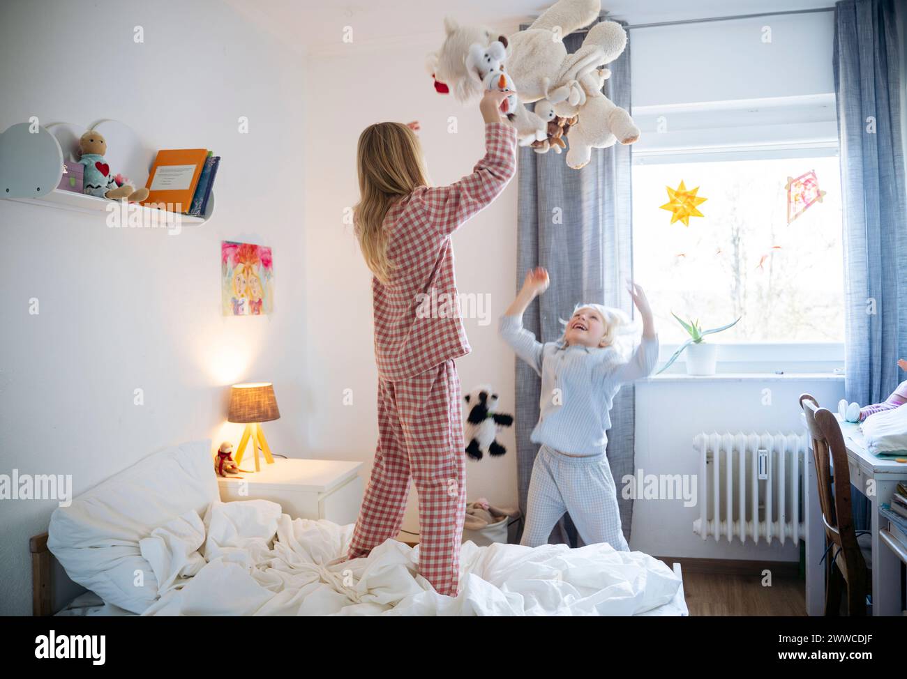 Playful siblings throwing teddy bear in bedroom at home Stock Photo