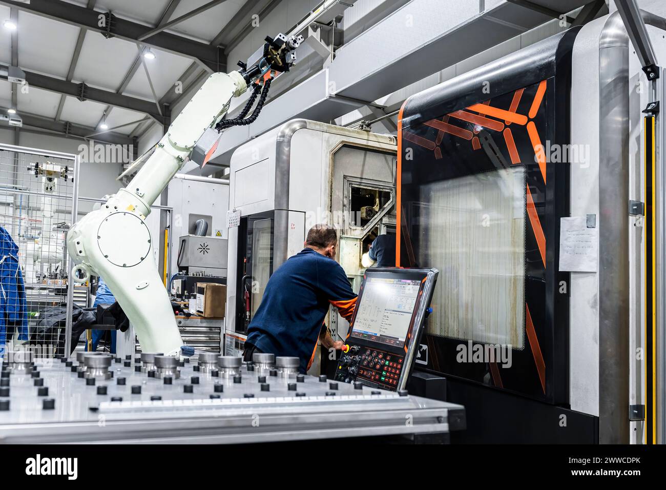 Mature maintenance engineer operating robotic machinery in modern factory Stock Photo