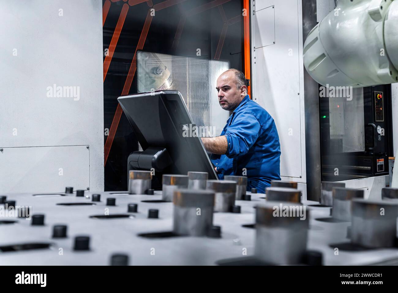 Technician operating CNC machine in modern factory Stock Photo