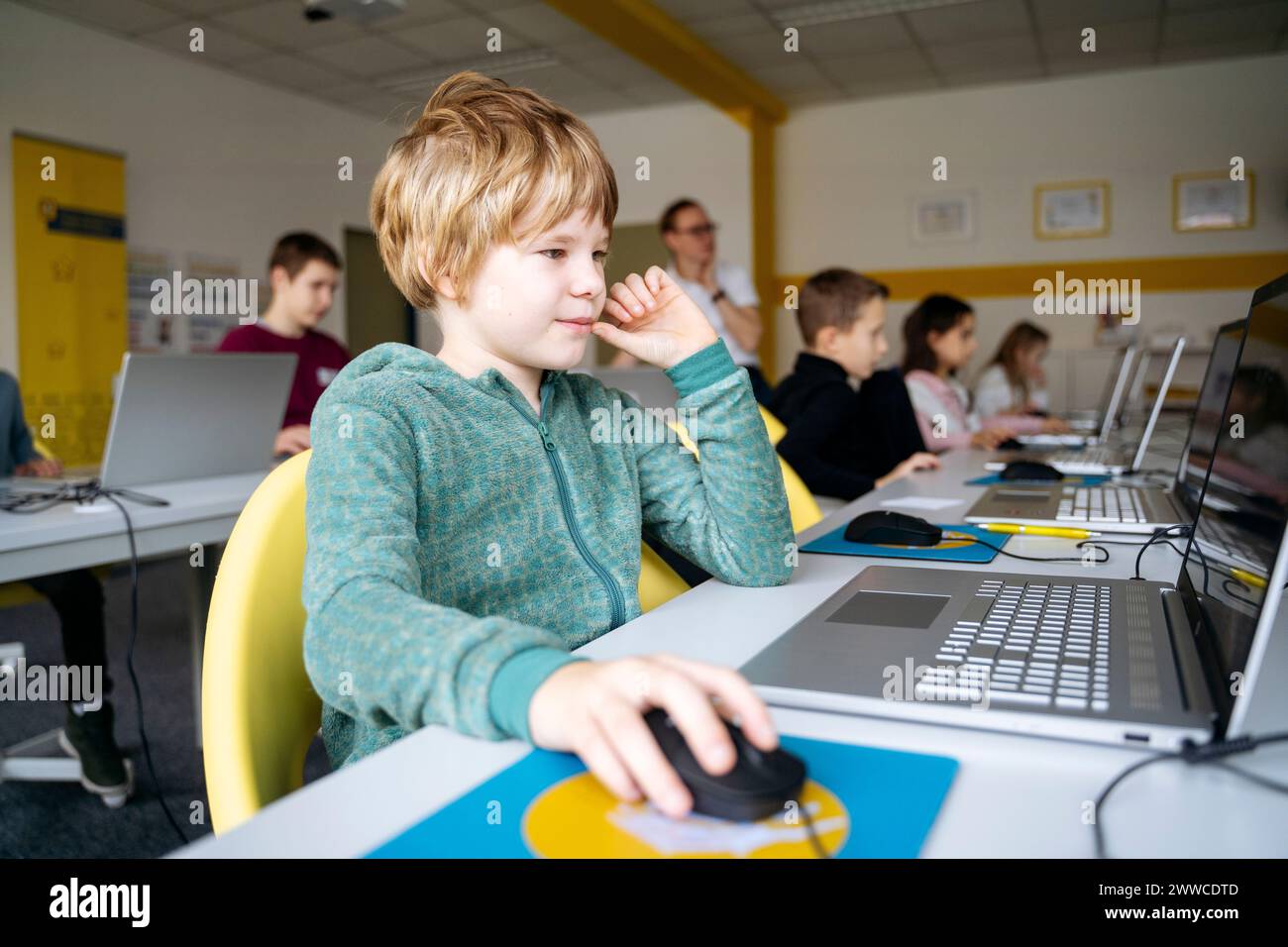 Blond boy learning computer coding through laptop in classroom Stock ...