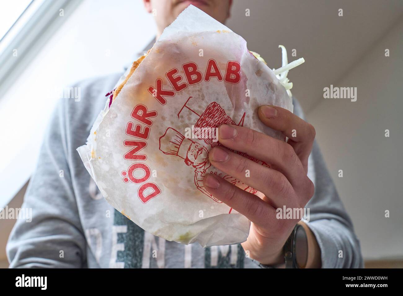 Augsburg, Bayern, Deutschland - 21 März 2024: Mann hält einen türkischen Döner Kebap in der Hand *** Man holding a Turkish doner kebab Stock Photo