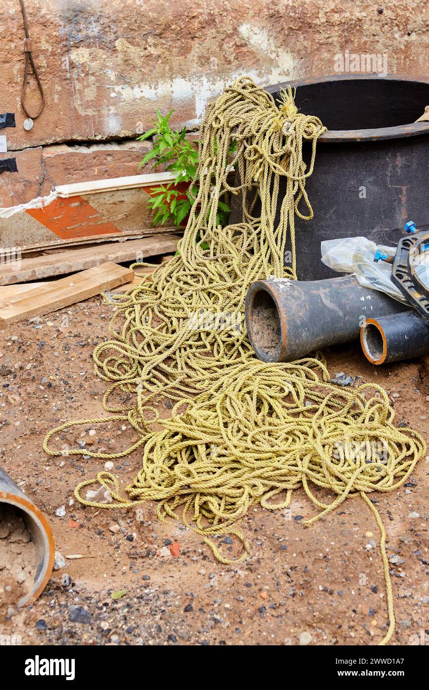Yellow Nylon Rope in a Heap and Cast Iron Pipes at Construction Site Stock Photo