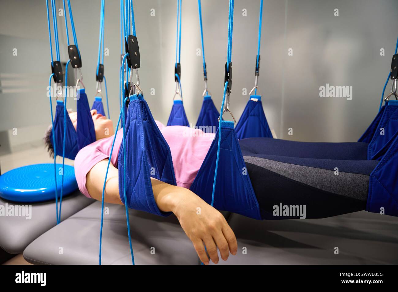 Middle aged woman hanging on suspension medical ropes after injury ...