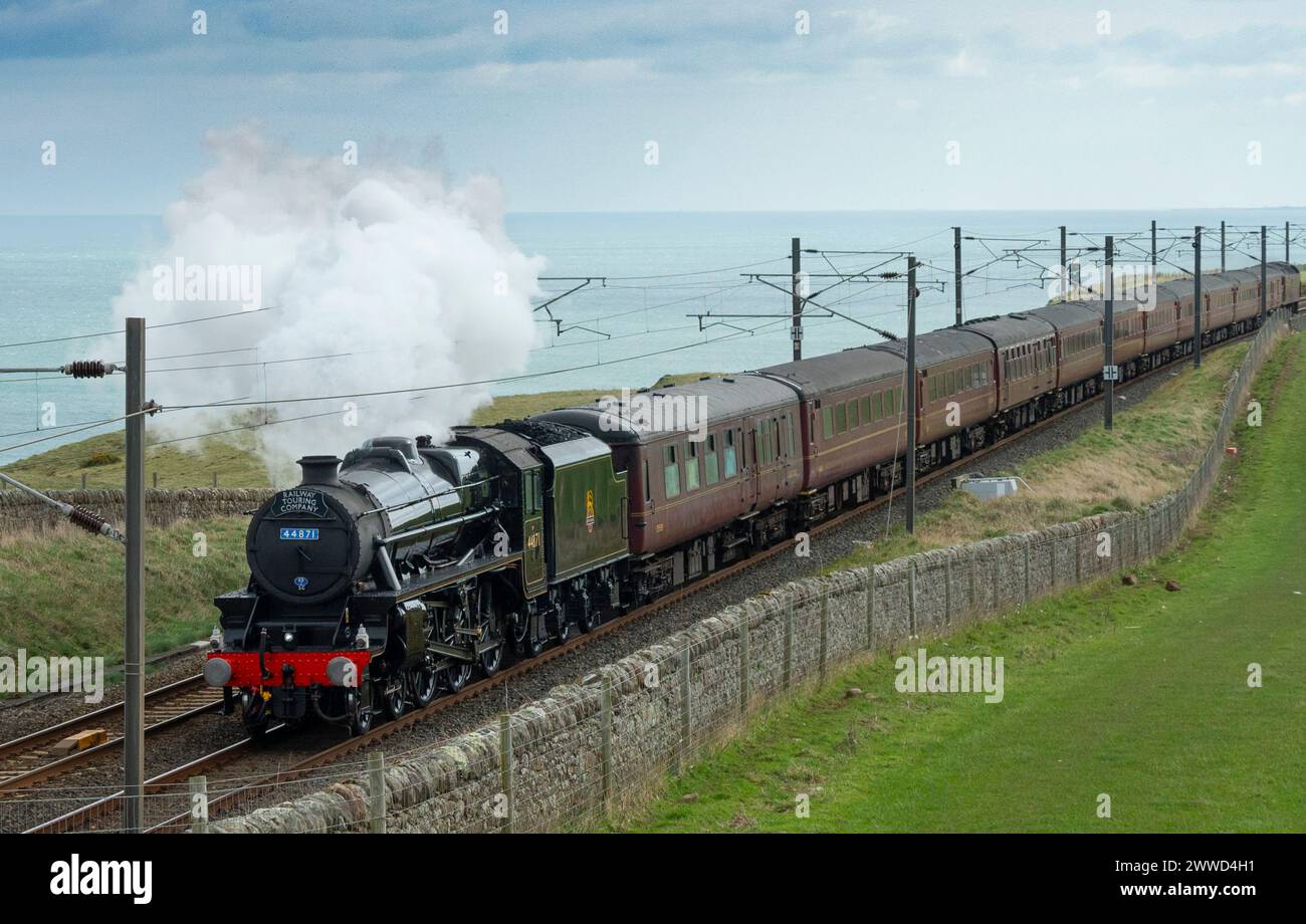 Lamberton, Scotland, UK. 23rd March, 2024. A rare Black 5 (or Class 5 Mixed Traffic) steam locomotive number 44871 operated by the Railway Touring Company pulls carriages carrying steam train enthusiasts on a day return excursion from York to Edinburgh. Pic; The locomotive is seen on the coast at Lamberton in the Scottish Borders near the  Scotland- England border. Iain Masterton/Alamy Live News Stock Photo