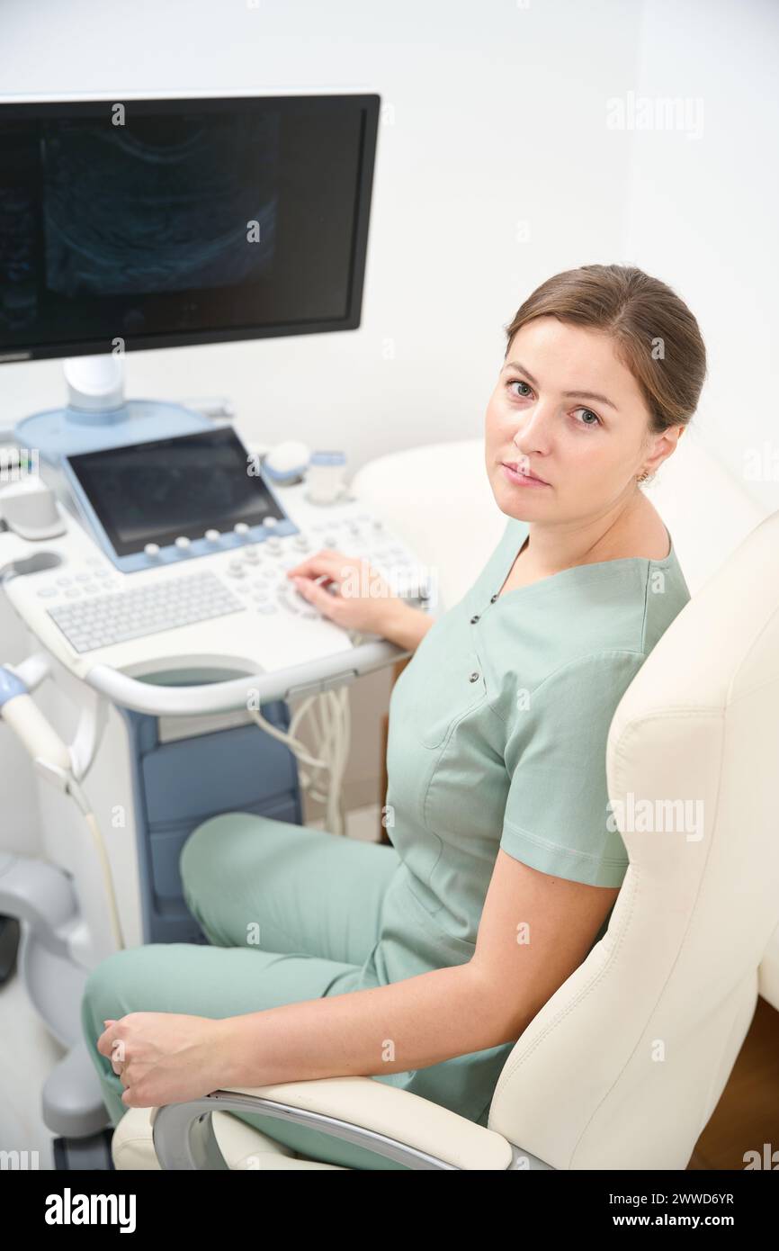 Serious female caucasian doctor working on blurred modern ultrasound machine Stock Photo