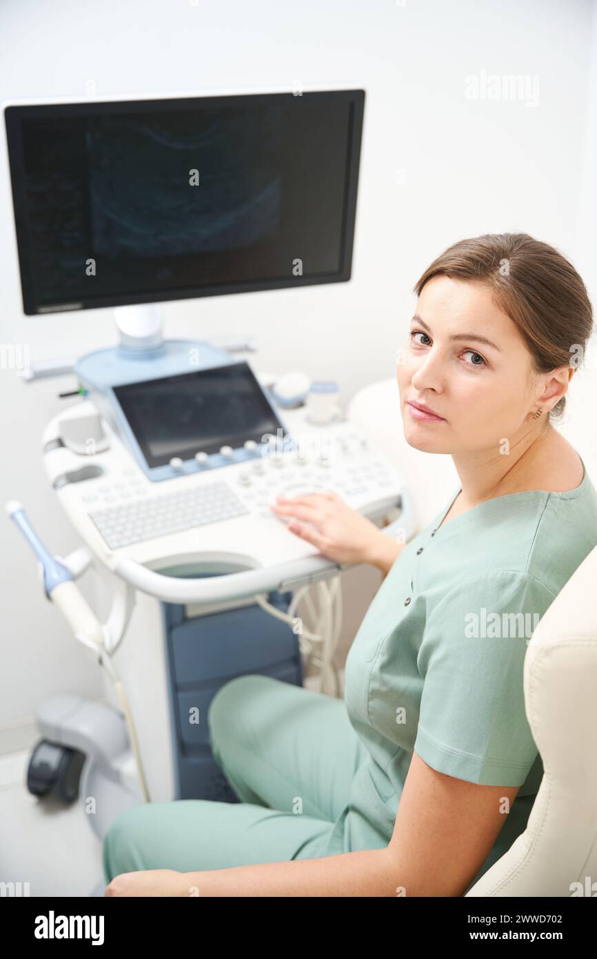 Doctor looking at camera while working on blurred modern ultrasound machine Stock Photo