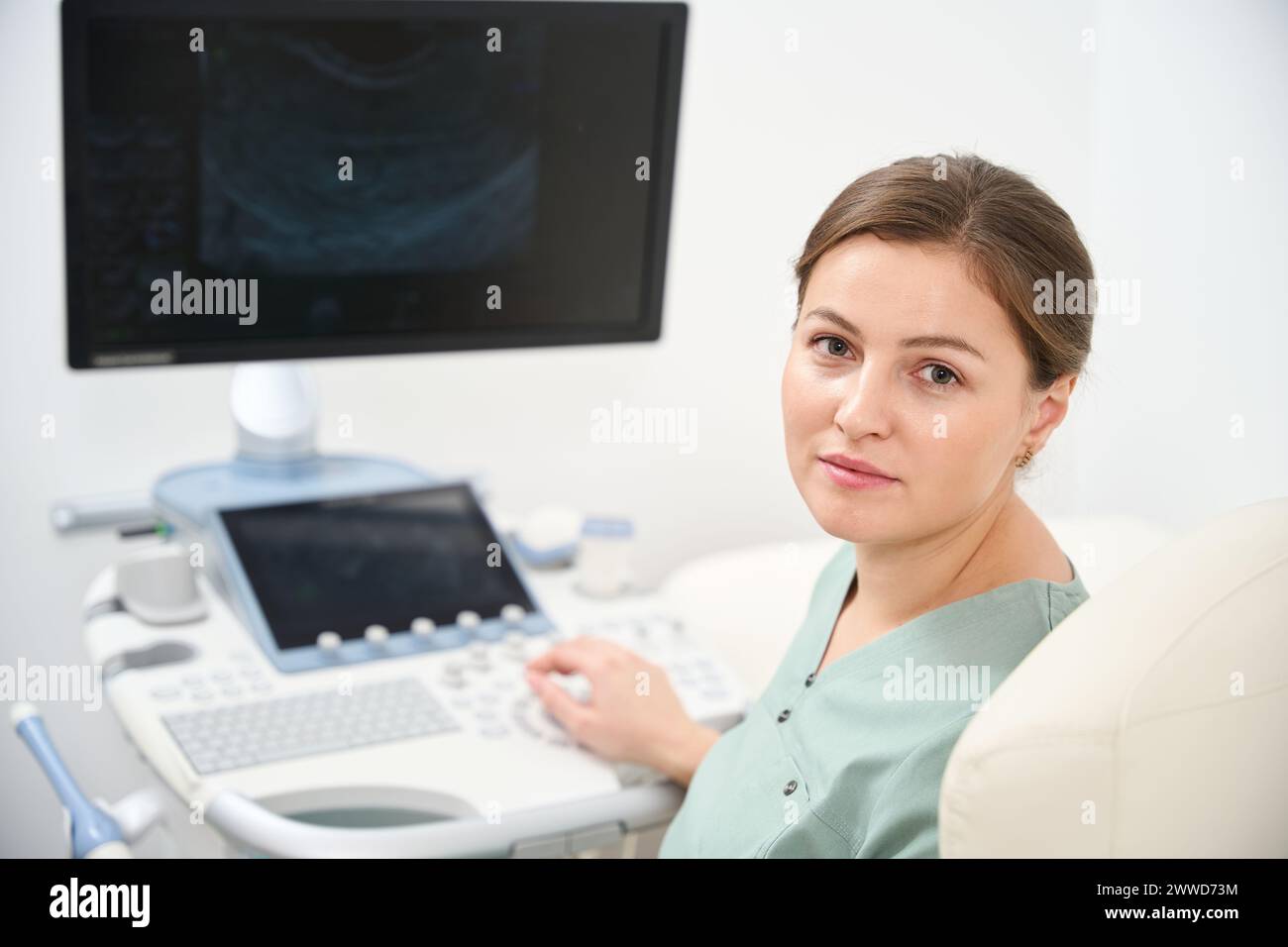 Female doctor looking at camera while working on ultrasound machine in clinic Stock Photo