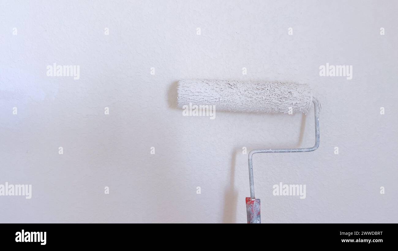 Painting a Wall with White Paint Roller Stock Photo - Alamy