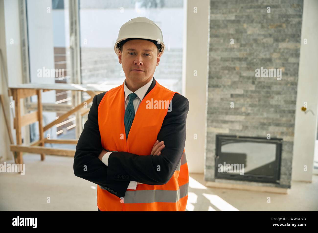 Construction engineer standing in room with folded arms across chest ...