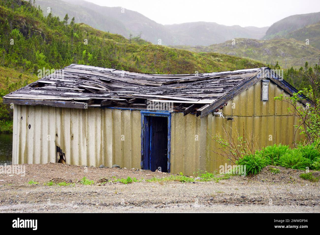 Tumbledown shed with sagging roof with rolling grass-covered hills in the background Stock Photo